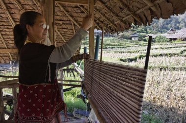 Tayland, chiang mai, karen uzun boyunlu tepe kabile Köyü (kayan lahwi), karen kadın geleneksel kostümleri bir halı yapıyor