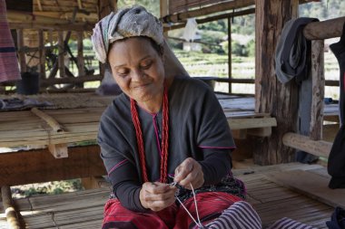 Tayland, chiang mai, karen uzun boyunlu tepe kabile Köyü (kayan lahwi), karen kadın geleneksel kostümleri bir halı yapıyor