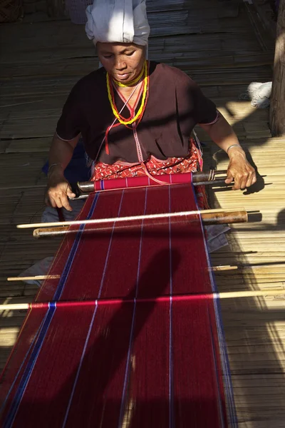 Thailand, Chiang Mai, Karen Long Neck hill tribe village (Kayan Lahwi), a Karen woman in traditional costumes is making a carpet — Stock Photo, Image