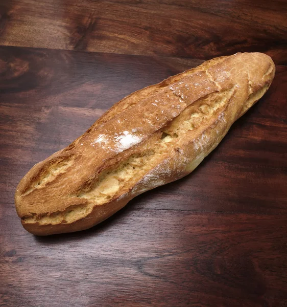 Pão italiano assado em uma mesa de madeira — Fotografia de Stock