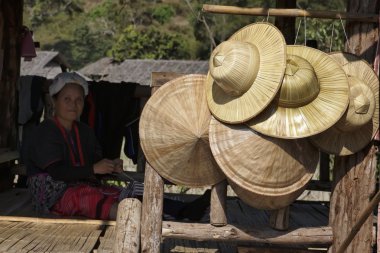 Thailand, Chiang Mai, Karen Long Neck hill tribe village (Kayan Lahwi), a Karen woman in traditional costumes and oriental hats for sale clipart
