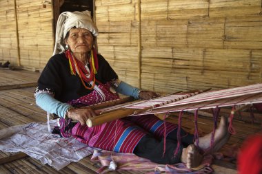 Thailand, Chiang Mai, Karen Long Neck hill tribe village (Kayan Lahwi), a Karen woman in traditional costumes is making a carpet clipart