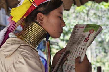 Tayland, chiang mai, karen uzun boyunlu tepe kabile Köyü (baan tong lhoung), uzun boyunlu kadın geleneksel kostümleri bir dergi okuma. 5 veya 6 yıl olduğunda kadınlar pirinç halkalar kendi boynuna koy.