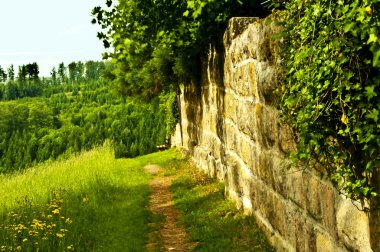 Eski bir manastır duvarındaki park bankında.