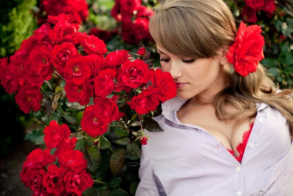 Młoda kobieta kwiat ogród pachnące róże czerwone — Zdjęcie stockowe