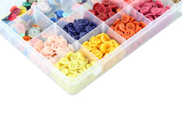 Wielu kolorowych przycisków skupić rogu w plastikowe pudełko na białym tle. — Zdjęcie stockowe