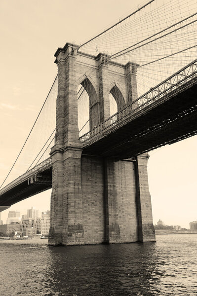 Brooklyn Bridge black and white over East River viewed from New York City Lower Manhattan waterfront.