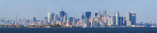 New York City lower Manhattan skyline with Statue of Liberty and urban city skyline over river panorama view.