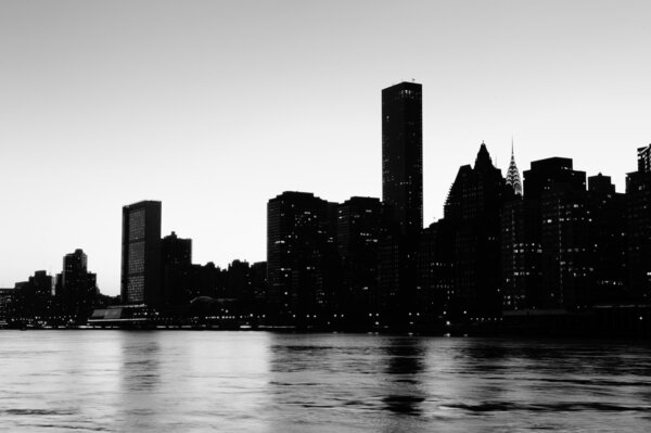 New York City midtown Manhattan sunset silhouette black and white panorama over East River at sunset.