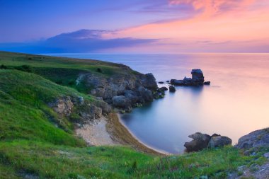 Amazing rocky coastline at sunset with the island