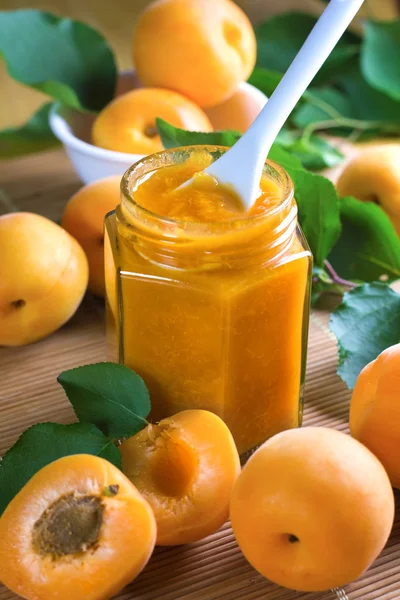 Apricot jam in jar and fresh fruits with leaves — Stock Photo, Image