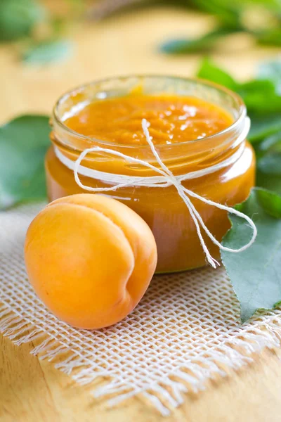 Apricot jam in jar and fresh fruit with leaves — Stock Photo, Image
