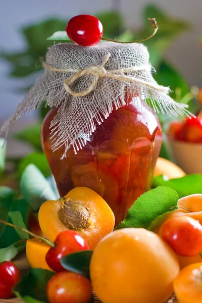 stock image Apricot and sweet cherry confiture in jar and fresh fruits with leaves