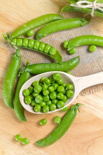 Fresh green peas on the wooden spoon — Stock Photo, Image