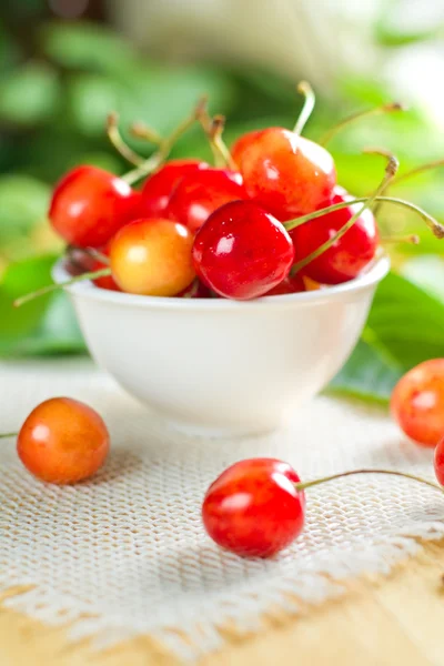 Wet sweet cherry on the white bowl and green leaves — Stock Photo, Image