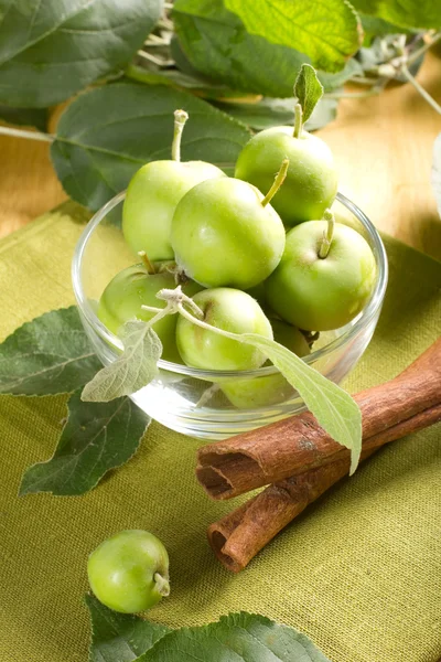 Small apples in the bowl and green leaves — Stock Photo, Image