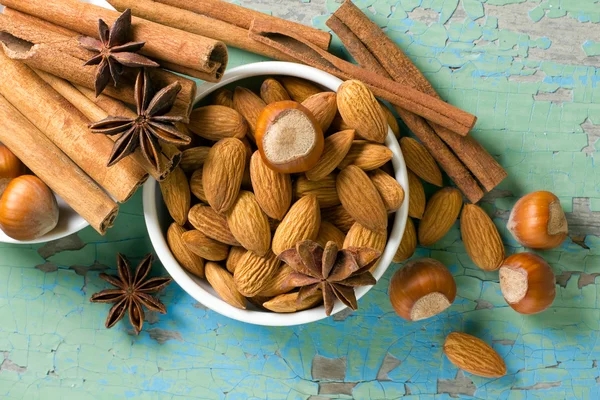 Aroma-Gewürze umrahmen. Zimt, Anis, Erdnüsse, Mandeln, Kardamom, Haselnüsse auf der Holzoberfläche. — Stockfoto