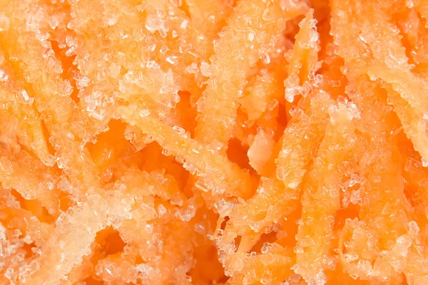 Тертая морковь на фоне сахара — стоковое фото