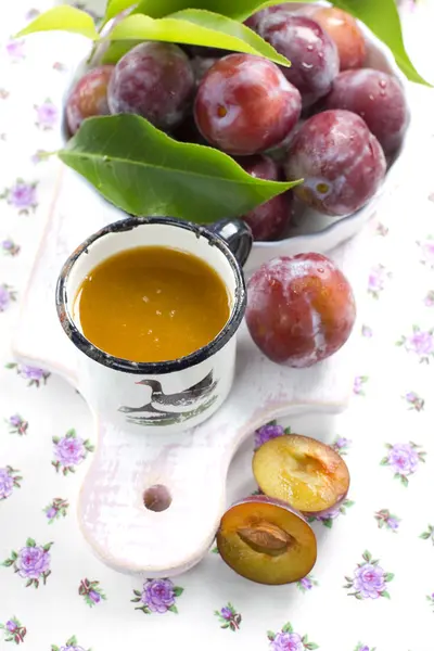 Švestkové šťávy a čerstvé ovoce s listy — Stock fotografie