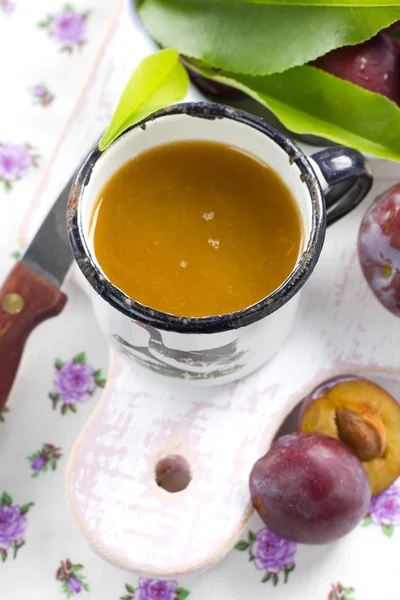 Plommon juice och färsk frukt med blad — Stockfoto