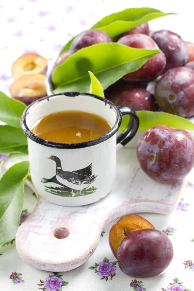 Plommon juice och färsk frukt med blad — Stockfoto
