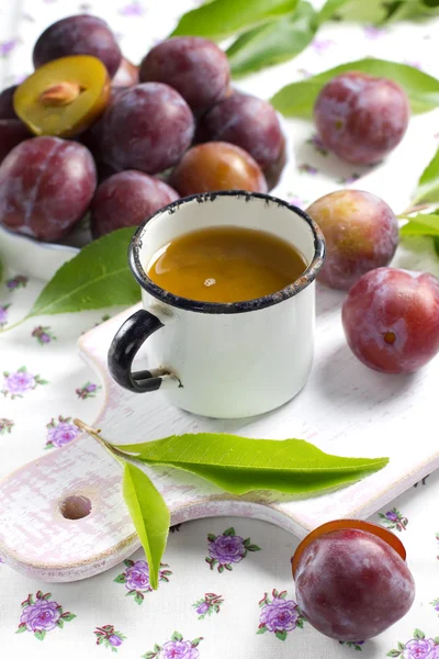 Švestkové šťávy a čerstvé ovoce s listy — Stock fotografie
