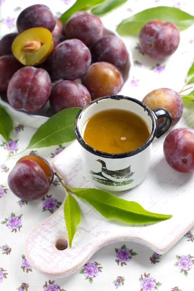 Suco de ameixa e frutas frescas com folhas — Fotografia de Stock