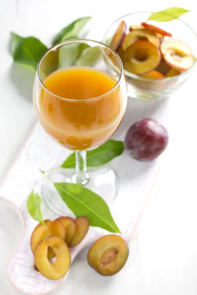 Suco de ameixa e frutas frescas com folhas — Fotografia de Stock