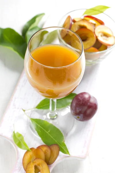 Succo di prugna e frutta fresca con foglie — Foto Stock