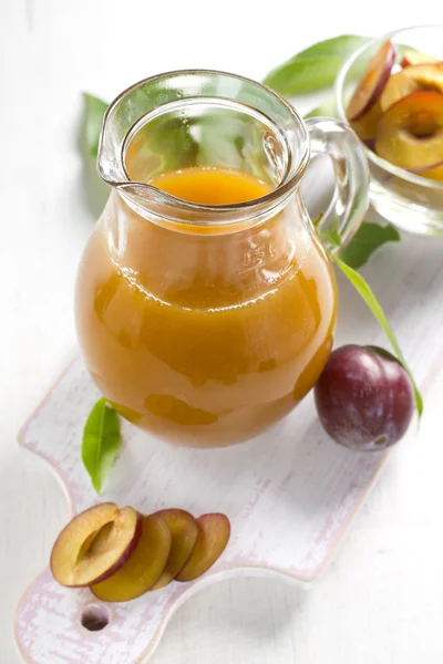 Szilva leve és friss gyümölcsökkel, levelekkel — Stock Fotó