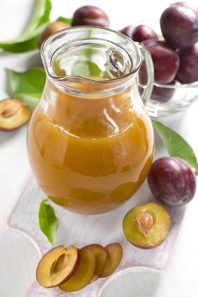 Szilva leve és friss gyümölcsökkel, levelekkel — Stock Fotó
