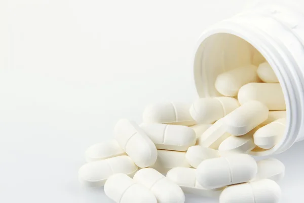 Piller som rinner från behållare på enfärgad bakgrund — Stockfoto