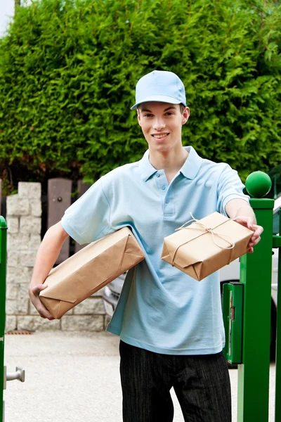 Young man from package courier brings — Stock Photo, Image