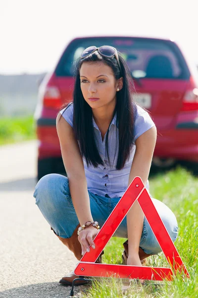 Женщина с предупреждающим треугольником в случае поломки — стоковое фото