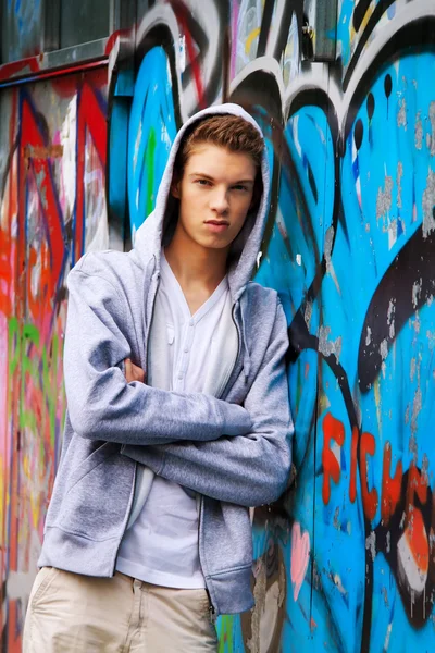 Fajny wygląd młodego człowieka przed graffiti — Zdjęcie stockowe