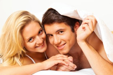 Couple has fun in bed. laughter, joy and eroticism clipart