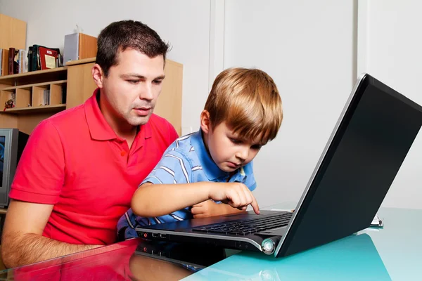 Homem e criança com computador portátil em casa . — Fotografia de Stock