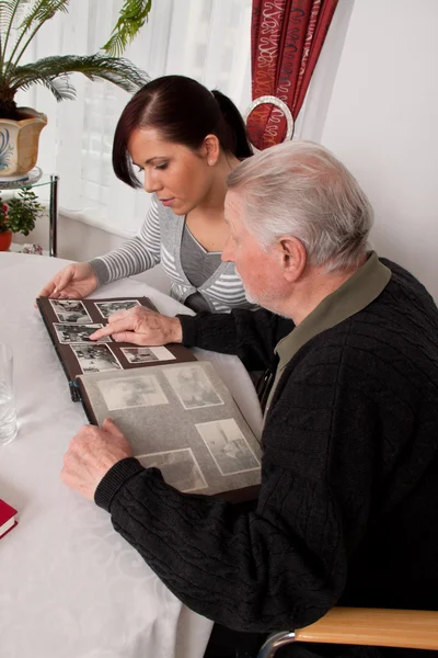 Mujer mirando un álbum de fotos con personas mayores — Foto de Stock