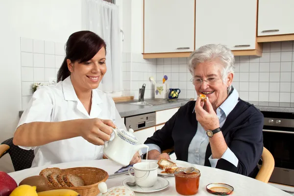 Enfermera ayuda a anciana en el desayuno — Foto de Stock