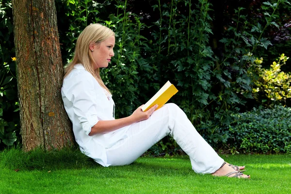 Kvinna läser bok i parken — Stockfoto