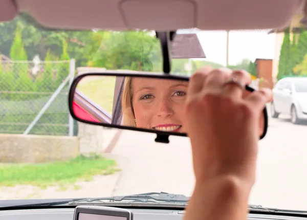 Mujer establece el espejo retrovisor en el coche —  Fotos de Stock