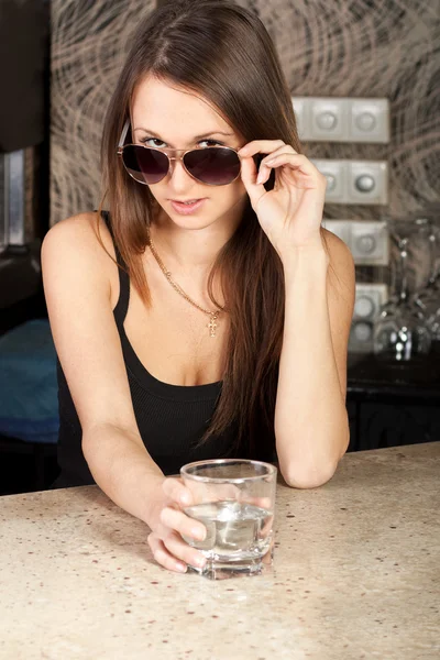 Stijlvolle brunette met een glas in een bar — Stockfoto