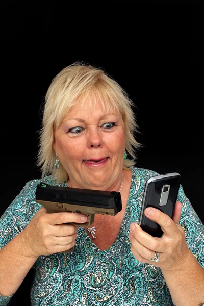 Зрелая блондинка с мобильным телефоном и пистолетом (2 ) — стоковое фото