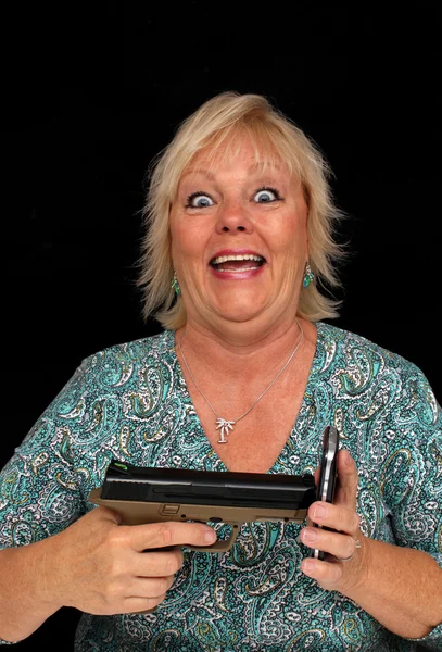 Oudere Blonde vrouw met mobiele telefoon en een pistool (5) — Stockfoto