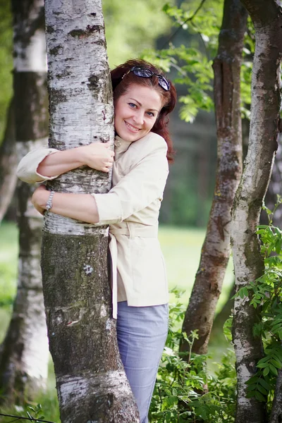 Mulher abraçando uma bétula — Fotografia de Stock