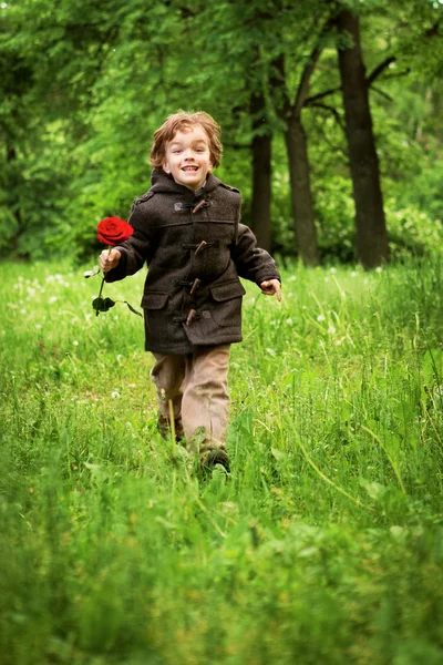 Rapaz feliz correndo na grama — Fotografia de Stock