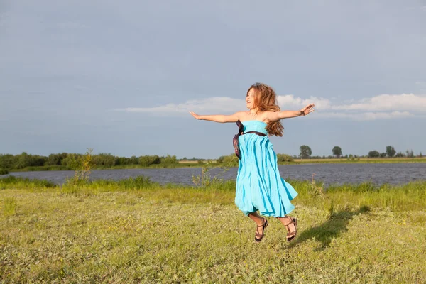 Petite fille drôle sautant sur le champ vert, été — Photo