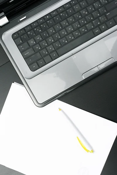 ノート パソコンと、テーブル上の空白の紙シート — ストック写真
