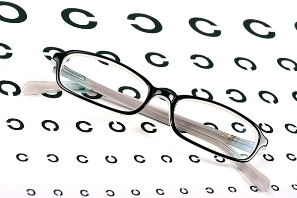 Black glasses on a eyesight test chart — Stock Photo, Image