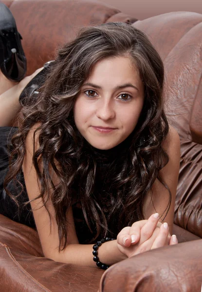 Pretty brunette woman's portrait with leather sofa in background